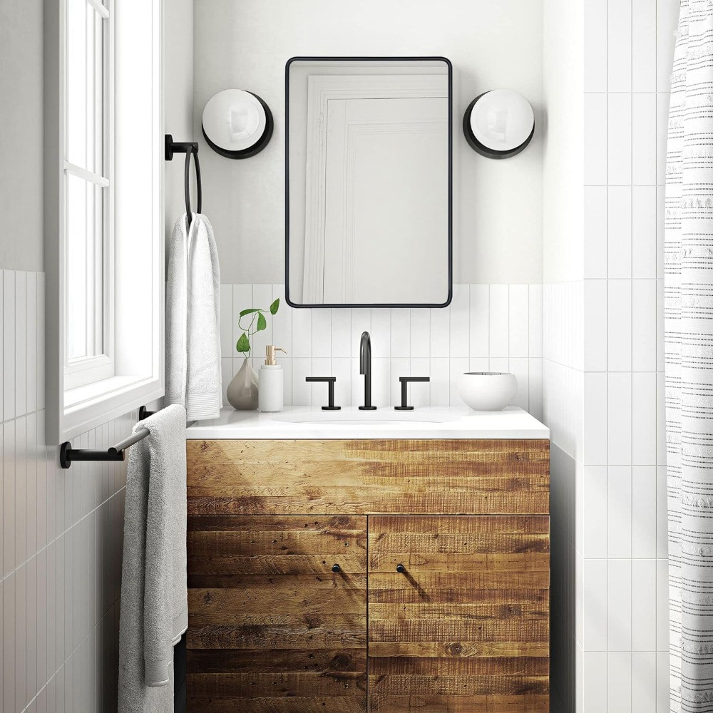 Mirror with black frame above wooden vanity in a bathroom